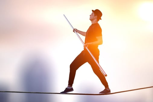 Concept of balance. Man walking on a tightrope and trying to stay on it. 
