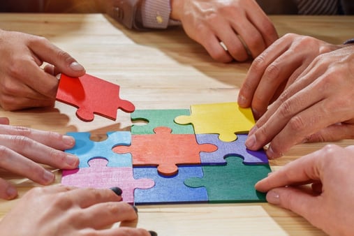 Concept of collaboration and shared goals. A team putting together pieces of a puzzle. 