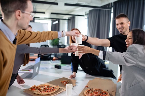 Employees eating pizza and having a toast 