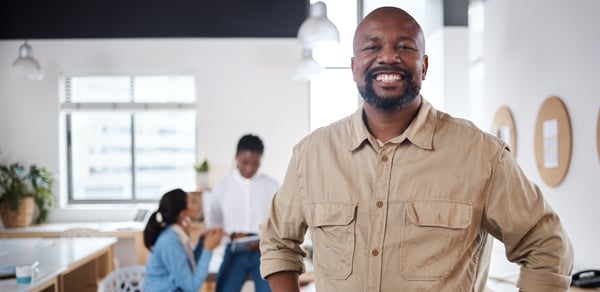Portrait of a confident mature businessman working in a modern office with his colleagues in the background