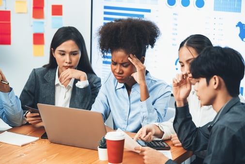 Diverse businesspeople analyzing financial dashboard data on laptop in serious meeting