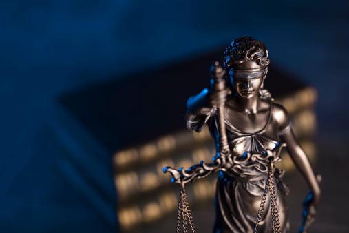 The concept of litigation. A statue of justice in front of a pile of law books. 