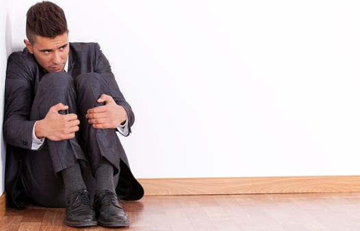 A businessman cowering in the corner. Concept of fearful employees and leadership. 