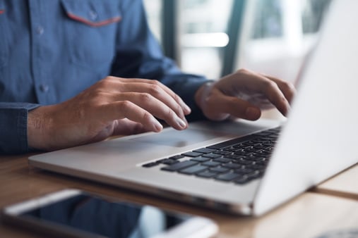 A professional-looking workspace with a laptop open to a compliance dashboard or data submission portal, symbolizing RxDC reporting