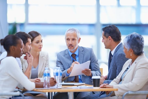 People sitting around a table, drinking water and talking