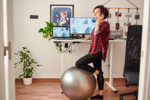 Young woman in plaid shirt standing at a remote work station 