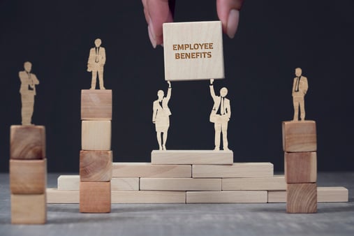 A sculpture of wooden people holding up a sign that says employee benefits