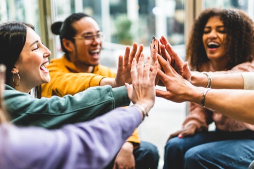 A group of individuals in a team giving each other a high five 