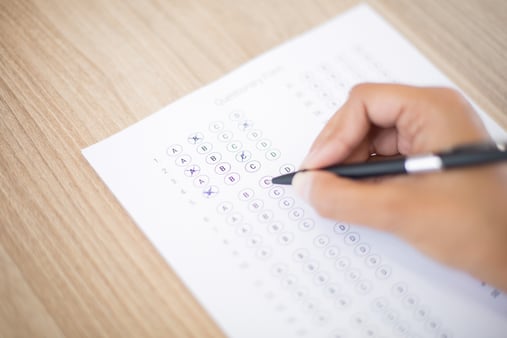 A hand holding a pen and filling out a quiz 