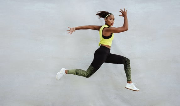 Powerful athletic black woman in exercise clothes mid-leap