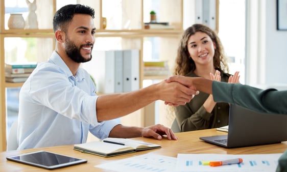 Man shaking hands with a person while someone applauds