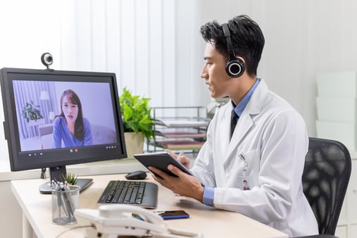 Doctor meeting with a telehealth patient in his office via a computer and webcam 