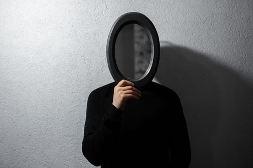 The concept of mirroring. A person holding a mirror in front of their face, where others are reflected and they lose their sense of self. 