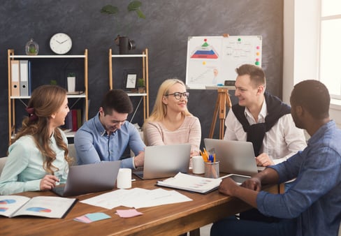 A collaborative team meeting unfolds in a bright, modern workspace where creativity meets productivity. The diverse group engages in lively discussion and brainstorming, surrounded by digital devices and colorful project materials, embodying a shared vision for innovation.