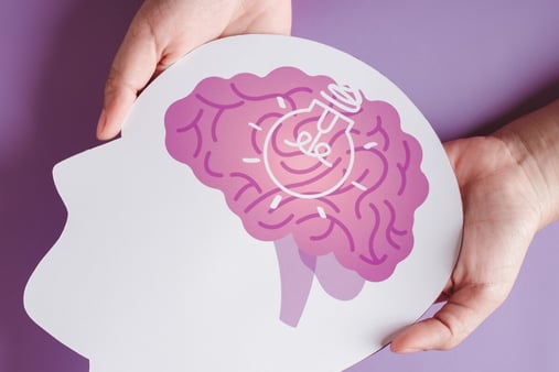 The concept of mental health. A hand holding a cutout head with a brain. 