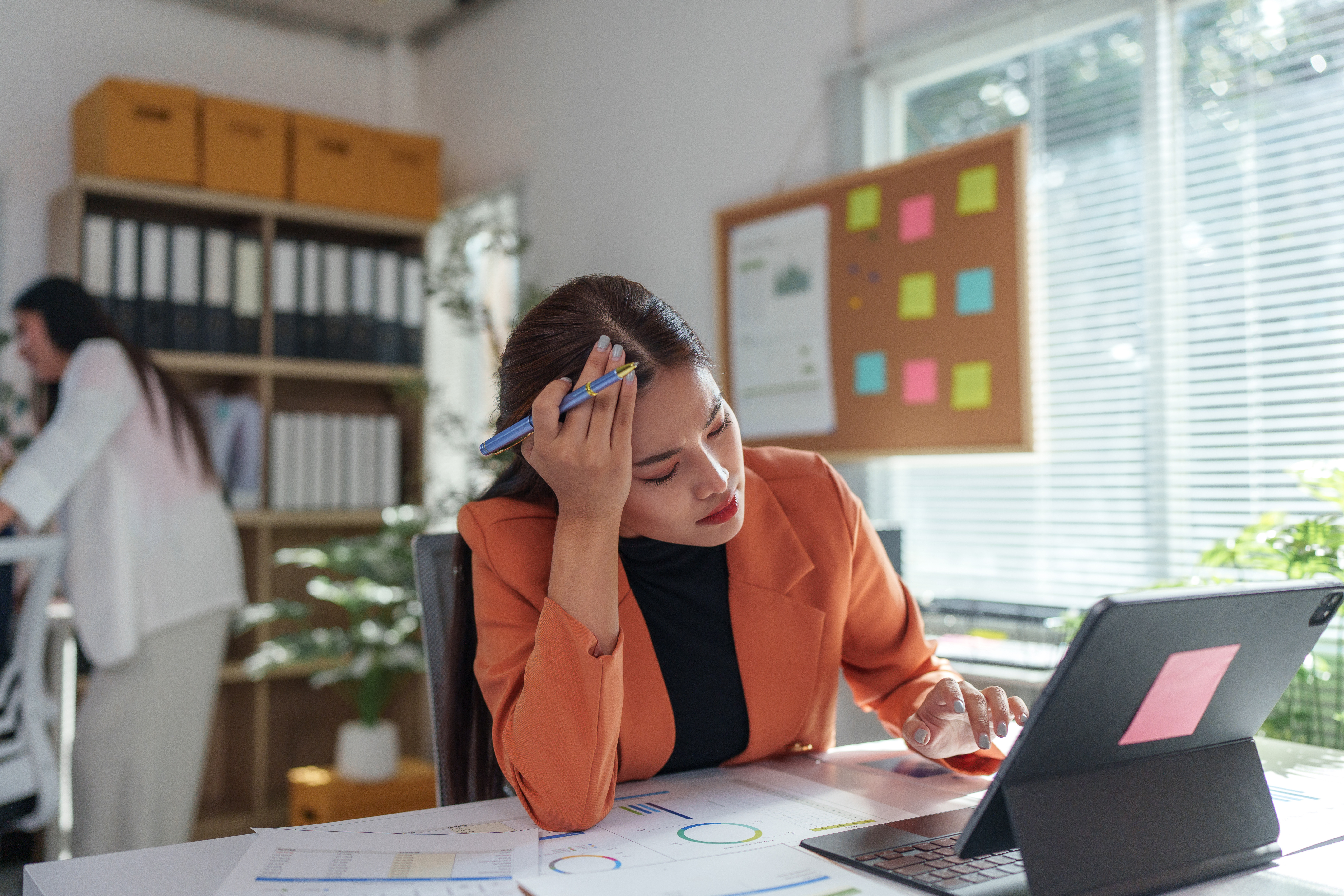 Concept of loneliness epidemic. Lonely employee working in the office with another employee in the background 